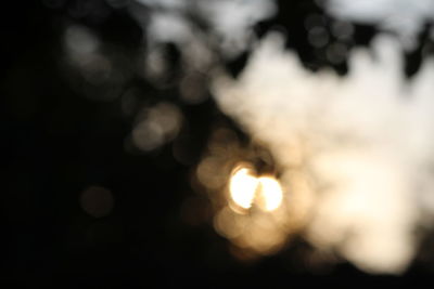 Defocused image of illuminated lights against sky at night