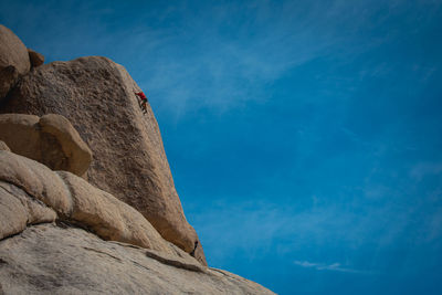 Low angle view of man on rock against sky