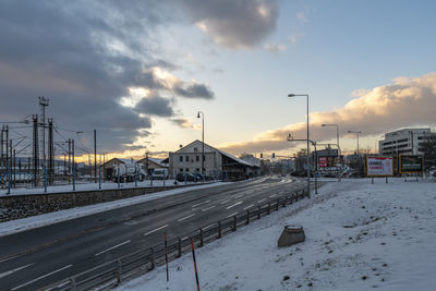 Snow covered road against sky during sunset