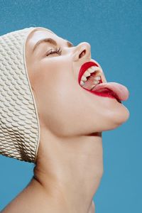 Low angle view of young woman against blue sky