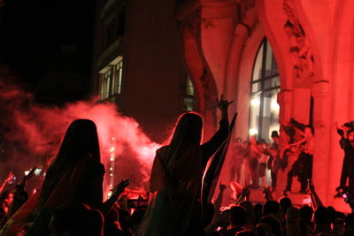 People in red fire hydrant at night