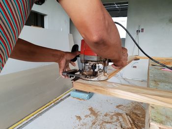 Cropped image of man cutting wood at workshop