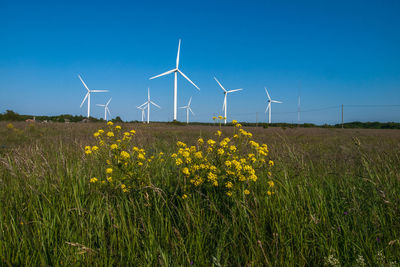 Wind turbines on field against sky