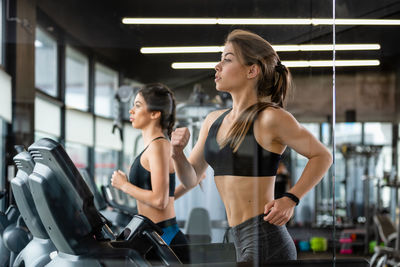 Beautiful young women running on treadmills in gym