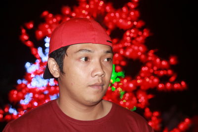 Young man wearing red cap looking away at night