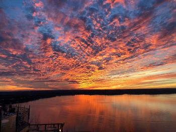 Scenic view of lake against dramatic sky during sunset