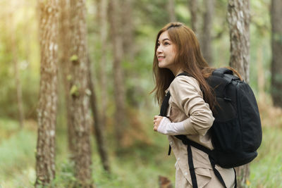 Young woman standing against trees