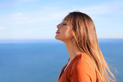 Young woman looking away against sea