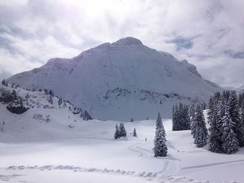 Scenic view of snow covered mountains against cloudy sky