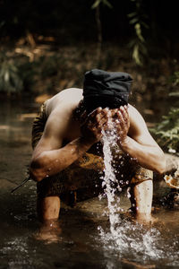 Rear view of shirtless boy playing in water