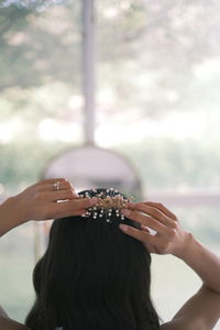 Cropped hand of woman looking through window