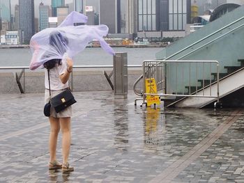 Full length of woman wearing raincoat while standing in city