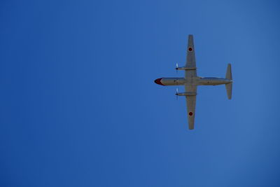 Low angle view of airplane in mid-air against clear blue sky