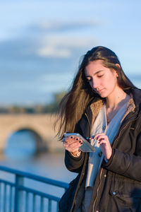 Portrait of young woman standing against sky