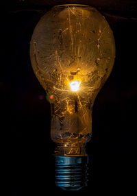 Close-up of illuminated light bulb against black background