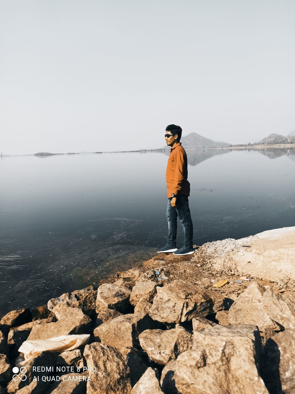 FULL LENGTH OF MAN STANDING ON ROCK AGAINST SKY