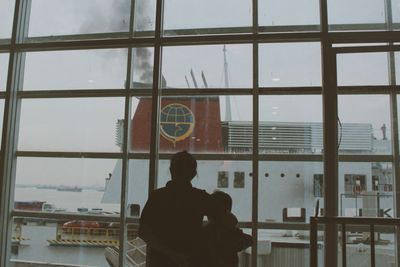 Rear view of silhouette man sitting in glass window