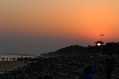 Silhouette people on beach against sky during sunset