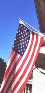 Low angle view of flags against clear blue sky