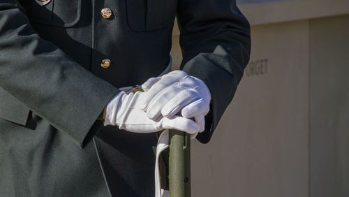 Midsection of military man with rifle standing outdoors
