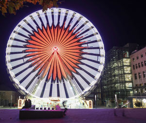 Illuminated ferris wheel in city at night