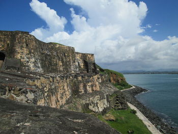 Scenic view of cliff by sea against sky