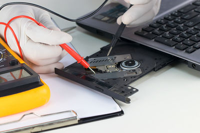 High angle view of technician repairing laptop dvd drive