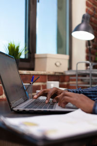 Cropped hand of man using laptop