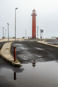 Reflection of lighthouse in puddle on road
