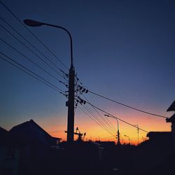 Low angle view of silhouette electricity pylon against sky