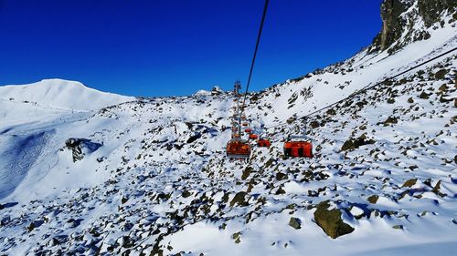 Ski lifts on snow covered mountains against sky
