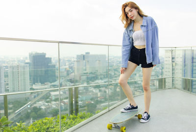 Portrait of woman standing against railing in city