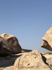 Rock formations on shore against clear blue sky