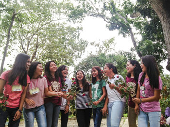 Low angle view of women standing against trees