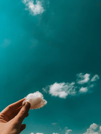 Person holding cotton against sky
