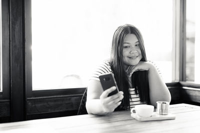 Portrait of woman using phone at coffee shop