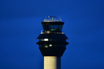 Low angle view of control tower by building against clear blue sky