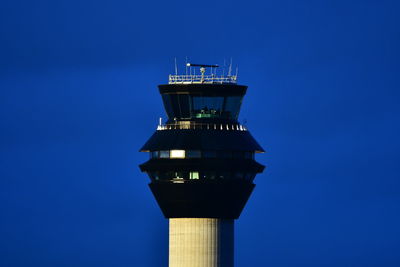 Low angle view of lighthouse by building against clear blue sky