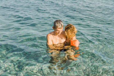Rear view of father and daughter in sea