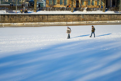 People walking on snow covered landscape during winter