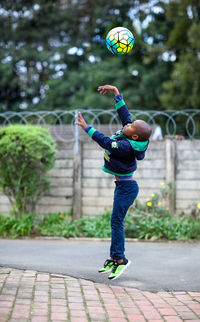 Full length of boy throwing ball on street