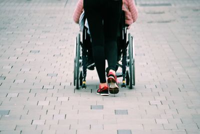 Low section of woman riding bicycle on footpath