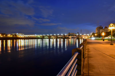 Illuminated bridge over river against sky at night