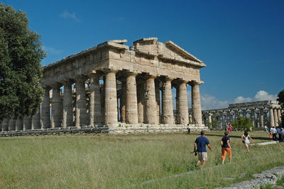 Tourists at old ruins against sky