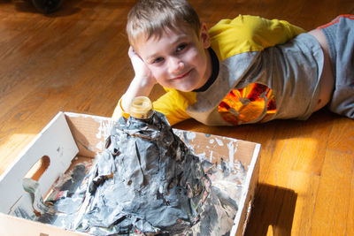 Portrait of smiling boy lying by artwork