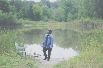 Rear view of man standing on field against trees