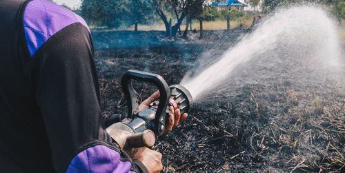 Midsection of man spraying water on land