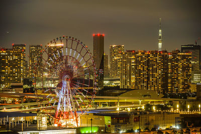 Illuminated ferris wheel in city at night