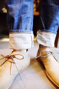 Low section of man standing on table with cool shoes