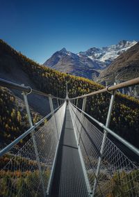 Footbridge over mountains against clear blue sky